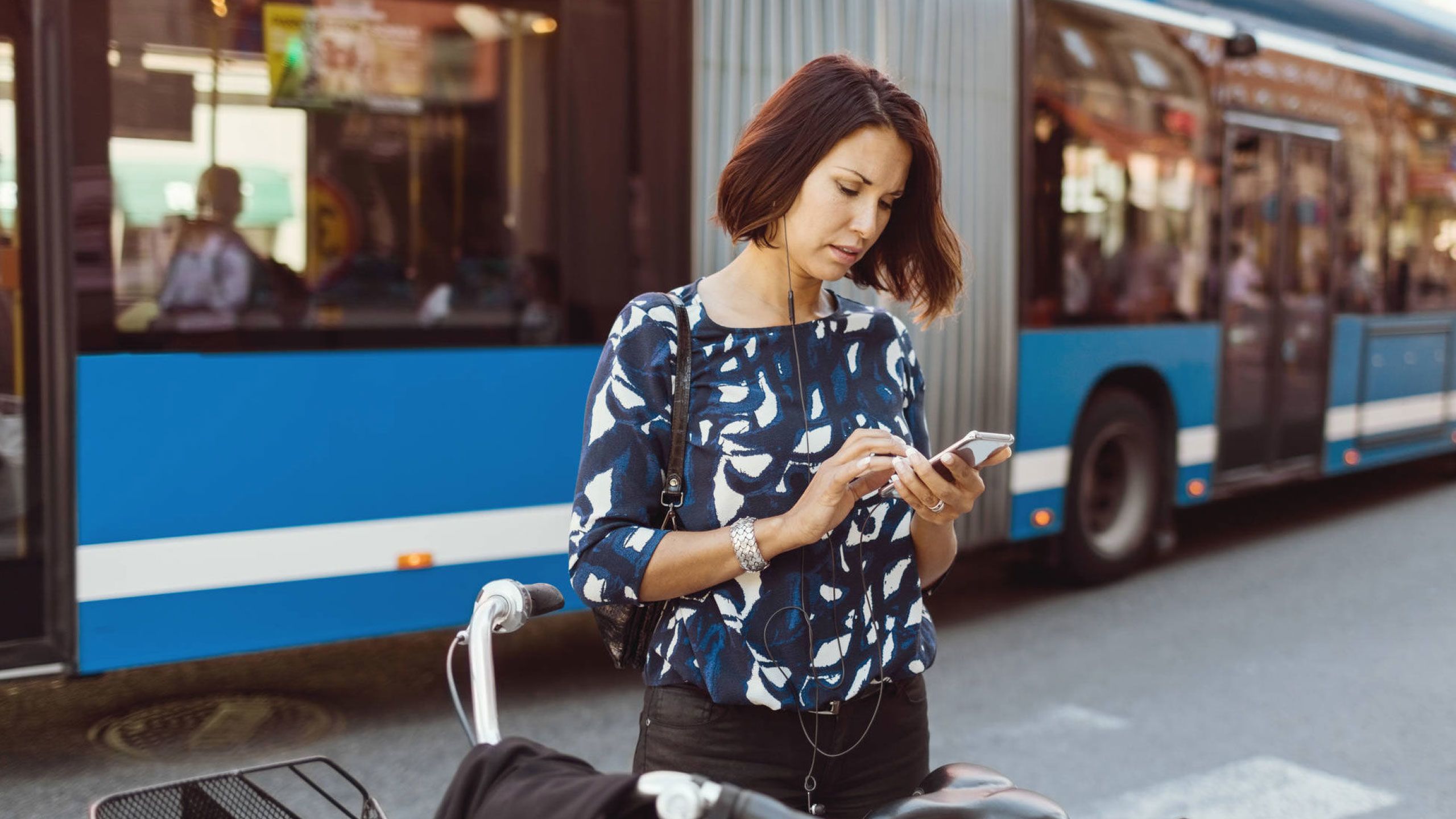YOUNG WOMAN USING PHONE WHILE SITTING ON STREET