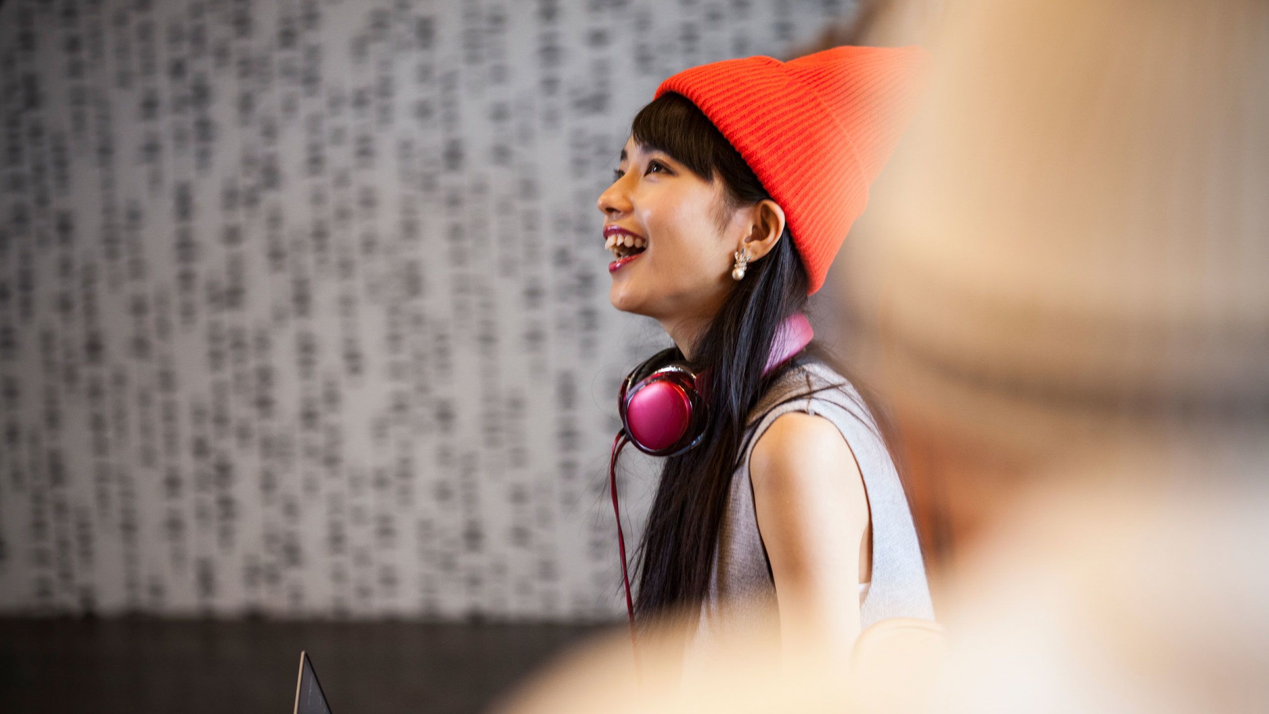 YOUNG WOMAN wearing orange hat and pink headphones around her neck